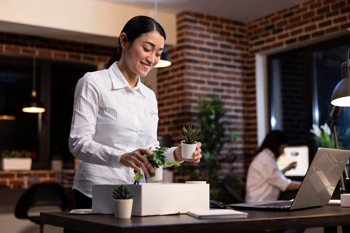 An Asian employee decorates a desk with plants.