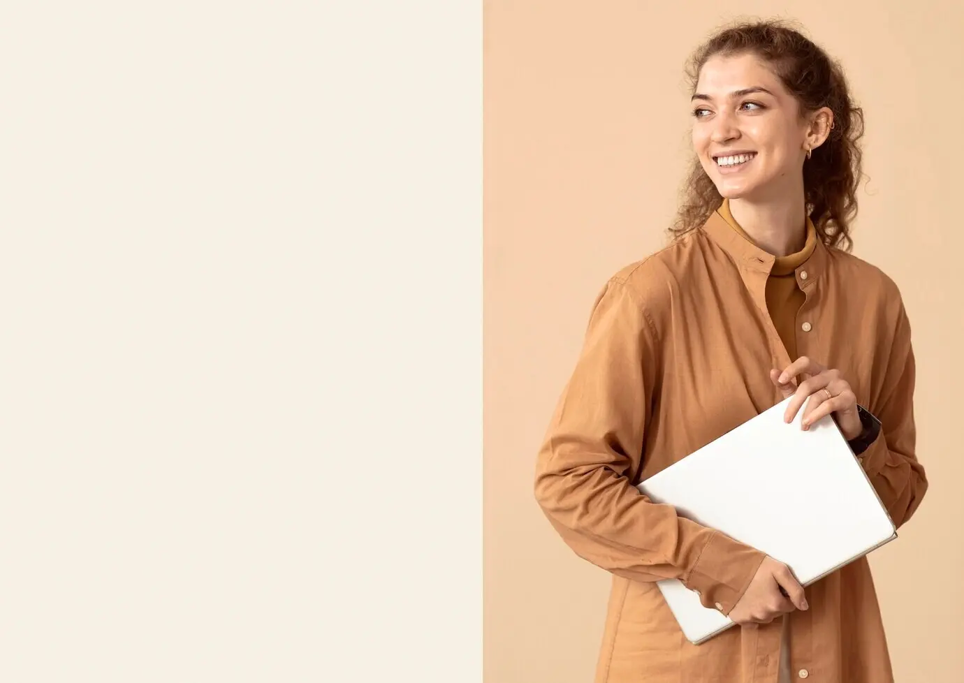 Woman looking off to the side while holding a laptop, with copy space.